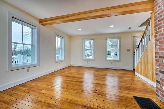 unfurnished living room with visible vents, beamed ceiling, wood-type flooring, baseboards, and stairs