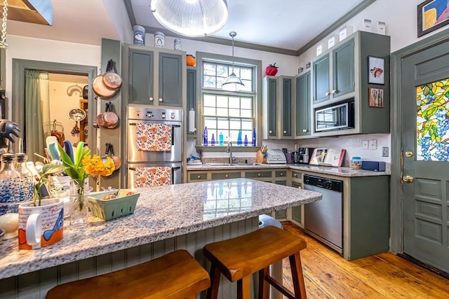 52 Central, Gardner, MA 01440 - kitchen with appliances with stainless steel finishes, a sink, a kitchen bar, light wood-style flooring, and light stone counters