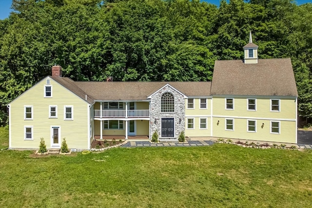 view of front of house with a balcony and a front yard