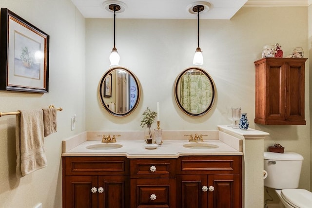 bathroom with toilet, double vanity, and a sink