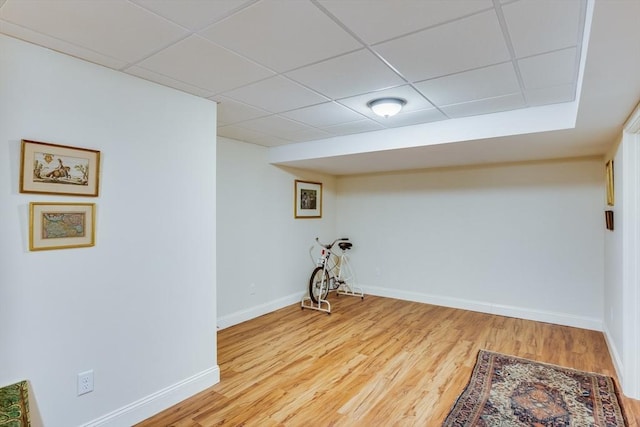 interior space featuring wood finished floors, a paneled ceiling, and baseboards