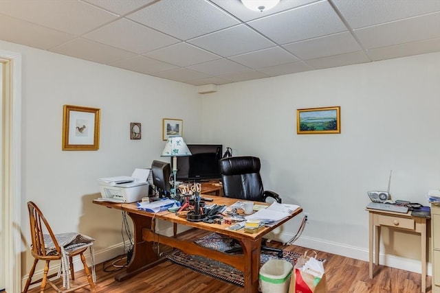 office area featuring wood finished floors, a paneled ceiling, and baseboards