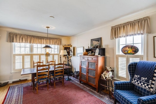 dining room featuring ornamental molding, baseboards, and wood finished floors