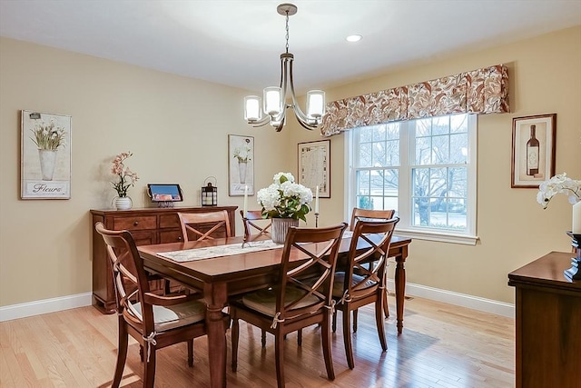 dining area with a chandelier, light wood finished floors, and baseboards