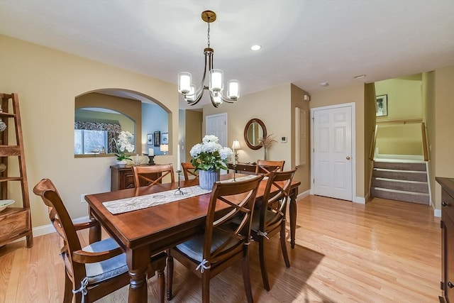 dining room with light wood-type flooring, baseboards, stairway, and a chandelier