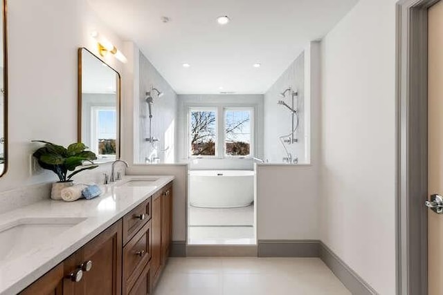 bathroom with a soaking tub, a sink, baseboards, and double vanity