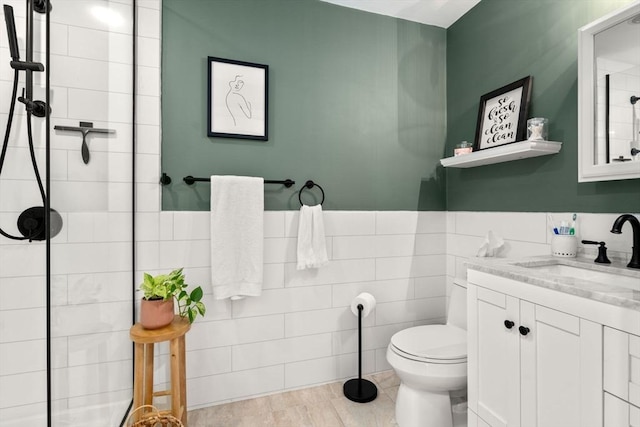 bathroom featuring vanity, tile walls, and toilet