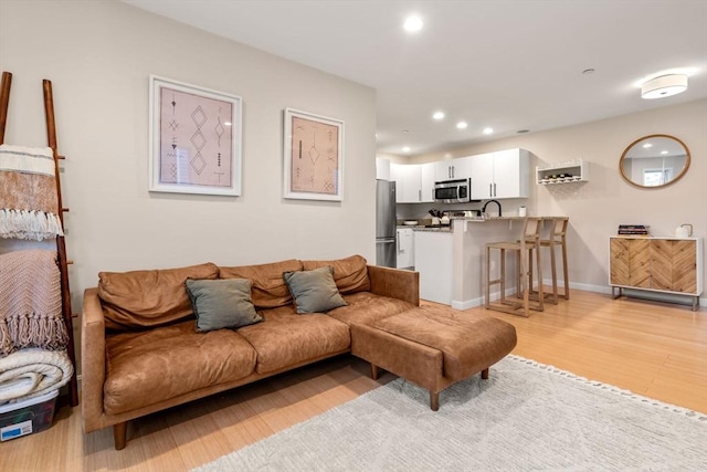 living room with sink and light hardwood / wood-style flooring