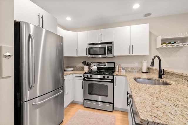 kitchen with white cabinetry, sink, stainless steel appliances, and light stone countertops