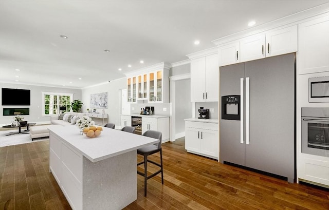 kitchen with dark hardwood / wood-style floors, a center island, stainless steel appliances, a kitchen bar, and white cabinets