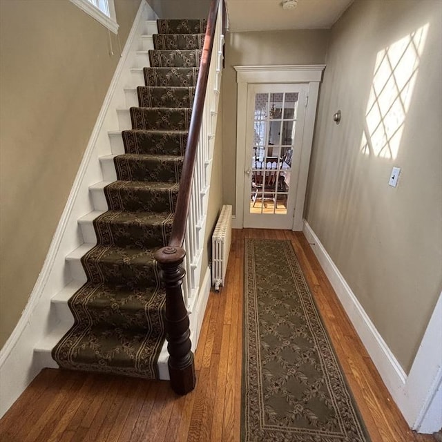 stairs with hardwood / wood-style flooring and radiator heating unit