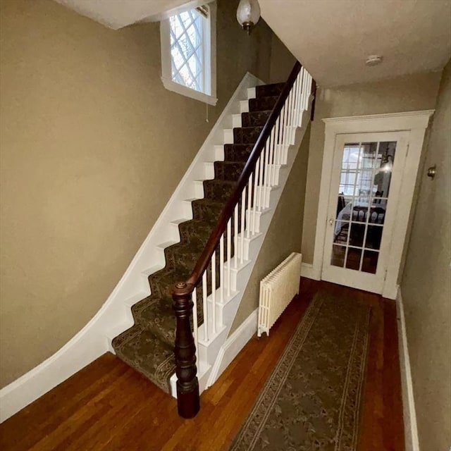 stairway with hardwood / wood-style flooring and radiator