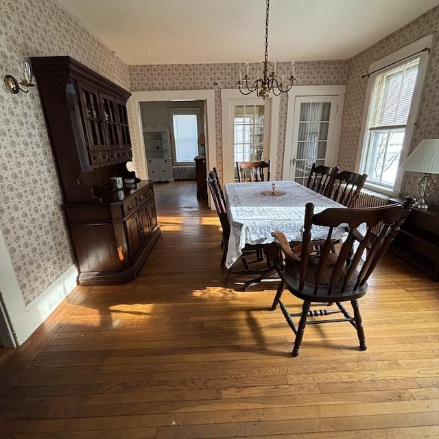 dining area with wood-type flooring and a notable chandelier