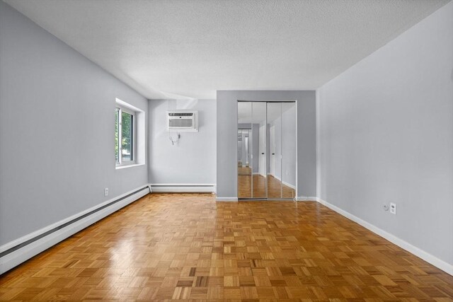 100 Park Terrace Dr Unit 124, Stoneham, MA 02180 - spare room with an AC wall unit, a baseboard radiator, baseboards, and a textured ceiling