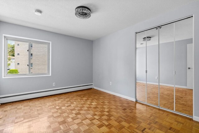 100 Park Terrace Dr Unit 124, Stoneham, MA 02180 - unfurnished bedroom with baseboard heating, a textured ceiling, baseboards, and a closet