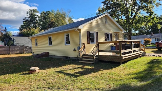 back of property with fence, a deck, and a yard