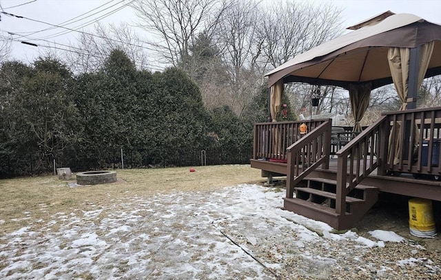 snowy yard featuring a wooden deck, a fire pit, and a gazebo