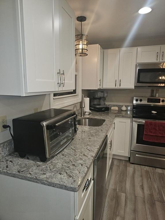 kitchen with white cabinetry, appliances with stainless steel finishes, dark wood-type flooring, and pendant lighting