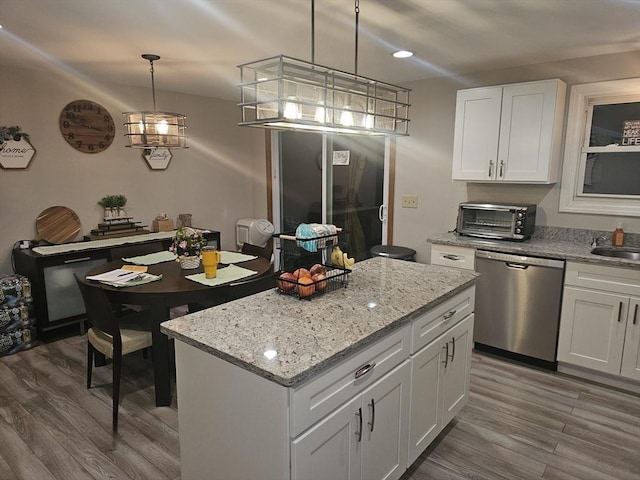 kitchen featuring dishwasher, white cabinetry, a center island, wood-type flooring, and decorative light fixtures