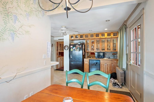 kitchen featuring tasteful backsplash, radiator, brown cabinetry, freestanding refrigerator, and beverage cooler