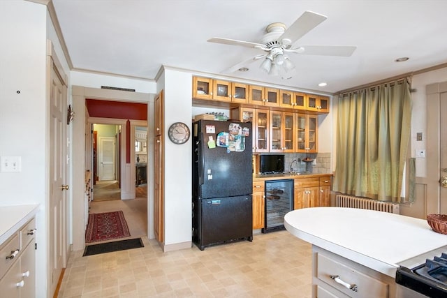 kitchen featuring brown cabinetry, wine cooler, glass insert cabinets, freestanding refrigerator, and light countertops