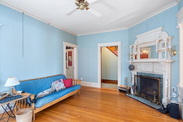 living room featuring ornamental molding, a fireplace, light wood-style flooring, and baseboards