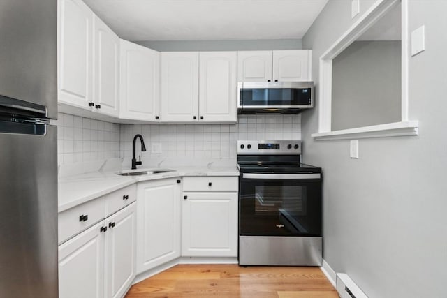 kitchen with sink, appliances with stainless steel finishes, white cabinets, and light stone countertops