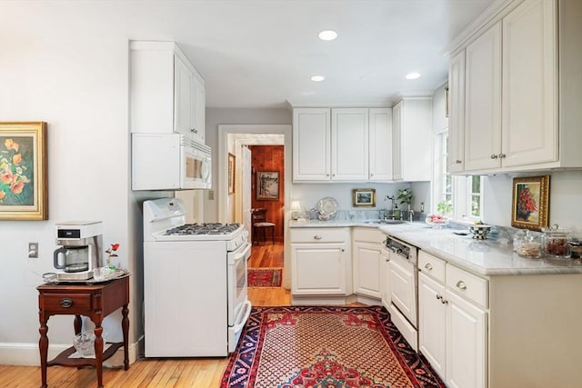 kitchen featuring white cabinets, white appliances, light hardwood / wood-style flooring, and sink