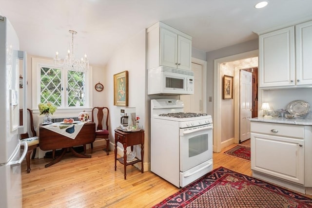 kitchen with white appliances, white cabinets, decorative light fixtures, light hardwood / wood-style floors, and a chandelier