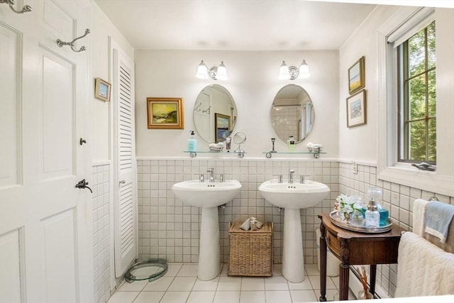 bathroom with double sink, tile patterned floors, and tile walls