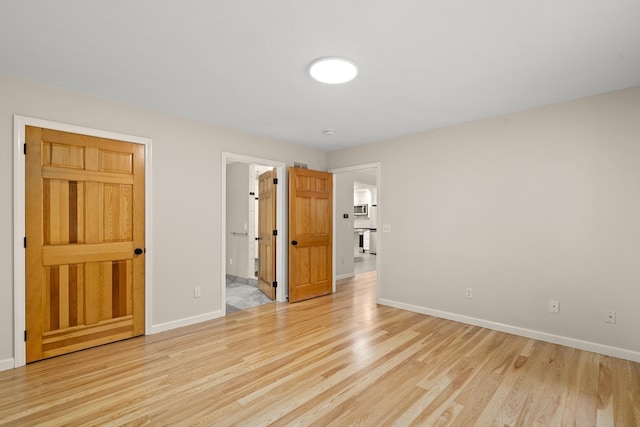 unfurnished bedroom featuring light hardwood / wood-style flooring and connected bathroom