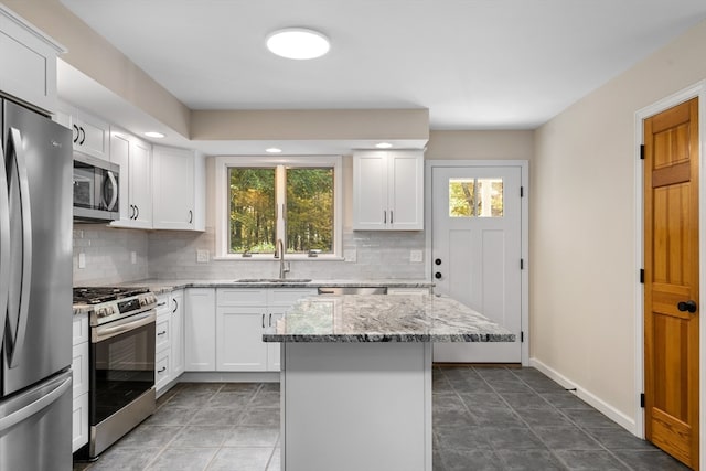 kitchen featuring light stone counters, stainless steel appliances, sink, and white cabinetry