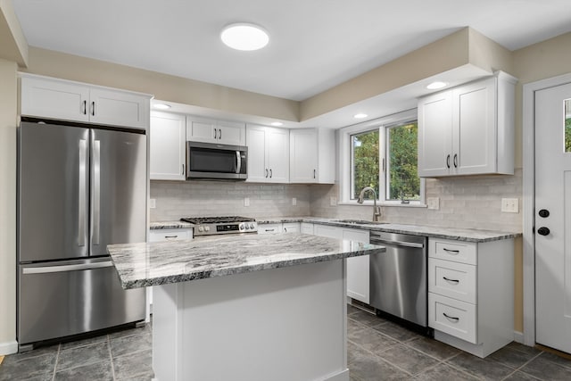 kitchen featuring white cabinets, a center island, appliances with stainless steel finishes, and sink