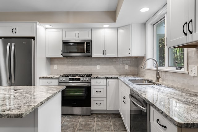 kitchen with backsplash, white cabinetry, sink, and stainless steel appliances