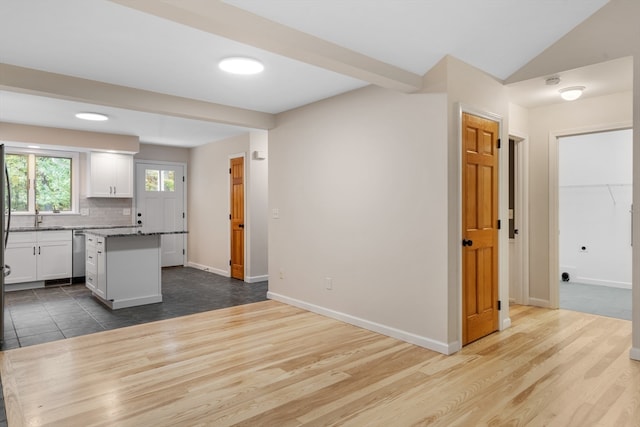 kitchen featuring white cabinets, hardwood / wood-style flooring, a kitchen island, and tasteful backsplash