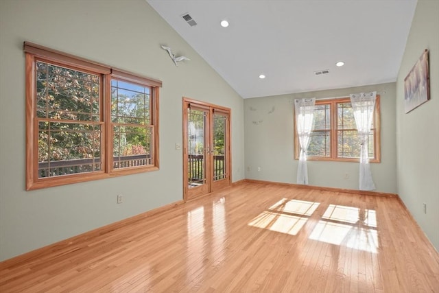 spare room with high vaulted ceiling, light wood-type flooring, and french doors