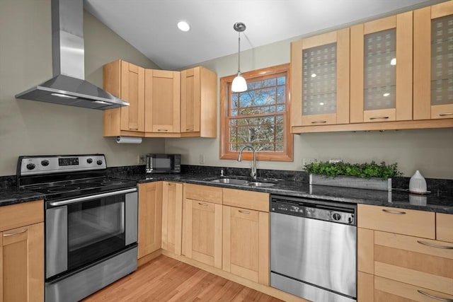 kitchen with pendant lighting, wall chimney range hood, sink, appliances with stainless steel finishes, and light brown cabinets