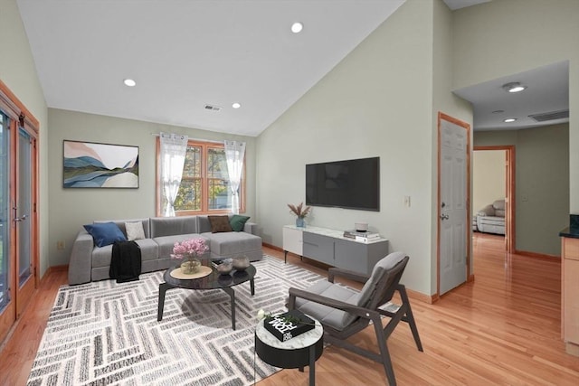 living room featuring high vaulted ceiling and light wood-type flooring