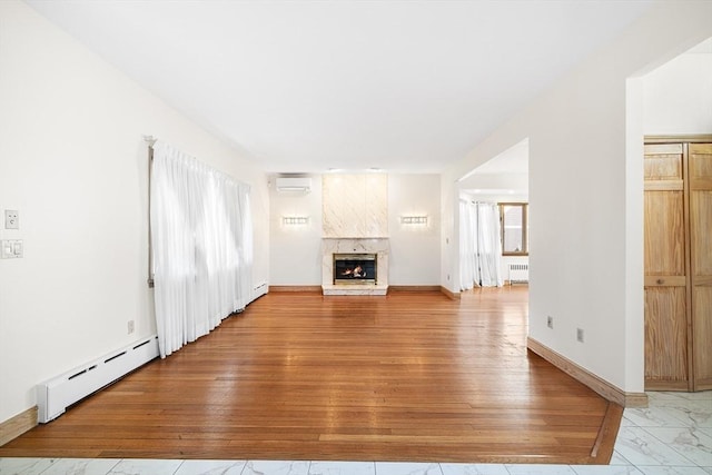 unfurnished living room featuring light wood-type flooring, an AC wall unit, a baseboard radiator, radiator, and a premium fireplace