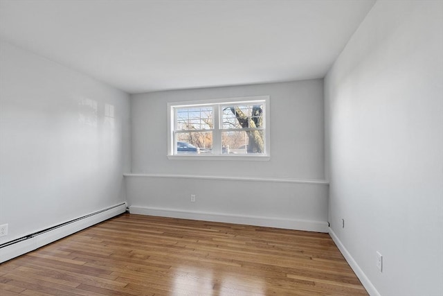 empty room with light hardwood / wood-style flooring and a baseboard heating unit