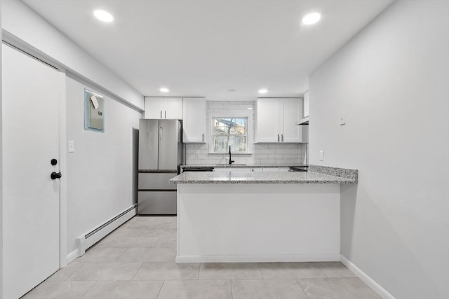 kitchen with stainless steel refrigerator, white cabinetry, sink, light stone counters, and a baseboard heating unit