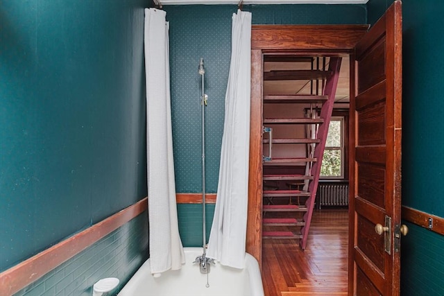 bathroom featuring radiator heating unit, parquet flooring, and shower / tub combo with curtain