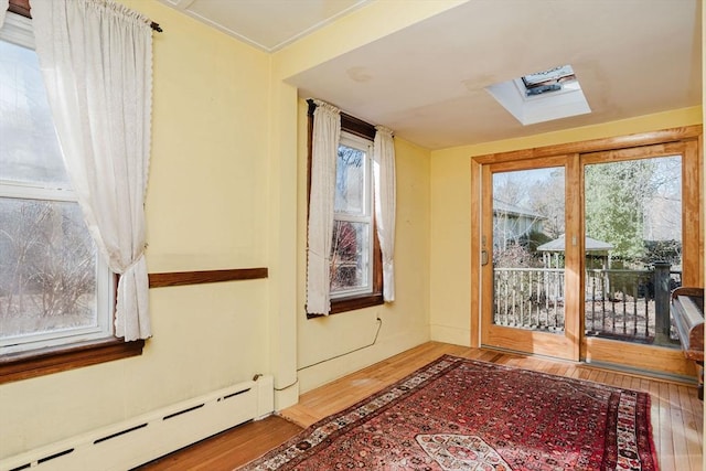 doorway to outside with baseboard heating, a skylight, and wood-type flooring