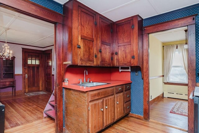 kitchen featuring sink, hanging light fixtures, an inviting chandelier, light hardwood / wood-style flooring, and a baseboard heating unit