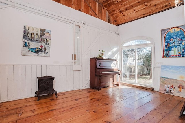 living area with a wood stove, wooden ceiling, lofted ceiling, and wood-type flooring