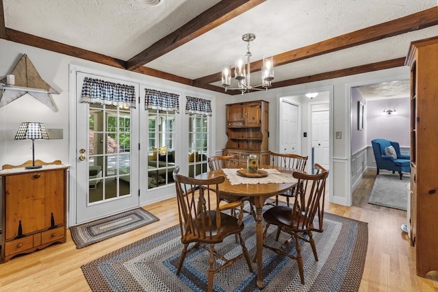 23 Fletcher St, Foxboro, MA 02035 - dining space with light wood finished floors, beam ceiling, a chandelier, and a wainscoted wall