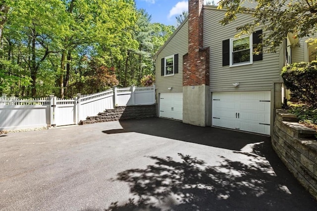 23 Fletcher St, Foxboro, MA 02035 - view of side of property featuring asphalt driveway, an attached garage, and a chimney