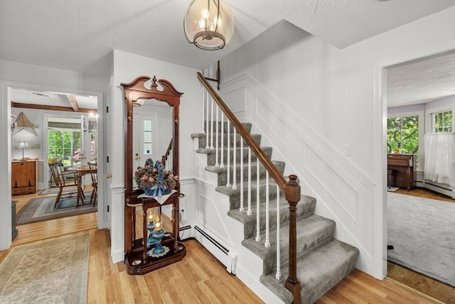 23 Fletcher St, Foxboro, MA 02035 - stairway featuring baseboard heating, wood finished floors, and a decorative wall
