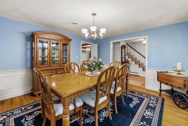 23 Fletcher St, Foxboro, MA 02035 - dining area with a chandelier, stairway, a wainscoted wall, a baseboard heating unit, and wood finished floors