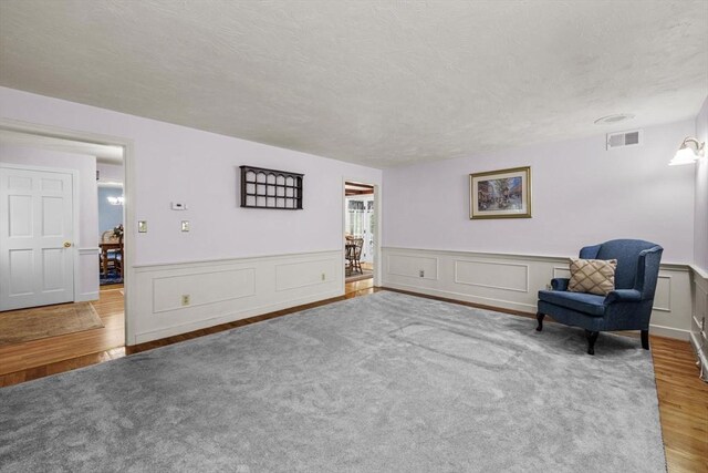 23 Fletcher St, Foxboro, MA 02035 - living area featuring wood finished floors, a wainscoted wall, and a textured ceiling